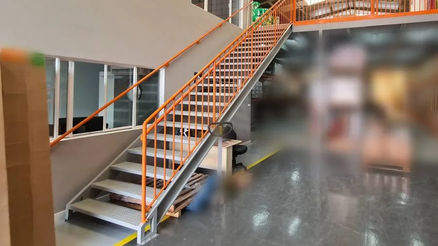 Escada metálica interna com guarda-corpo laranja instalada pela Metalsul